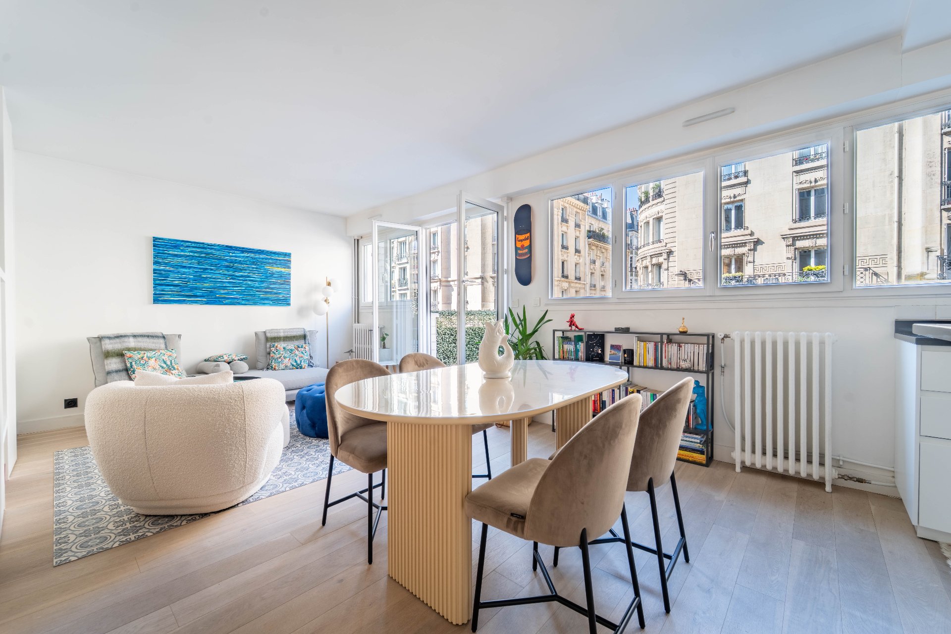 Salle à manger lumineuse avec table ovale et vue sur immeubles haussmanniens