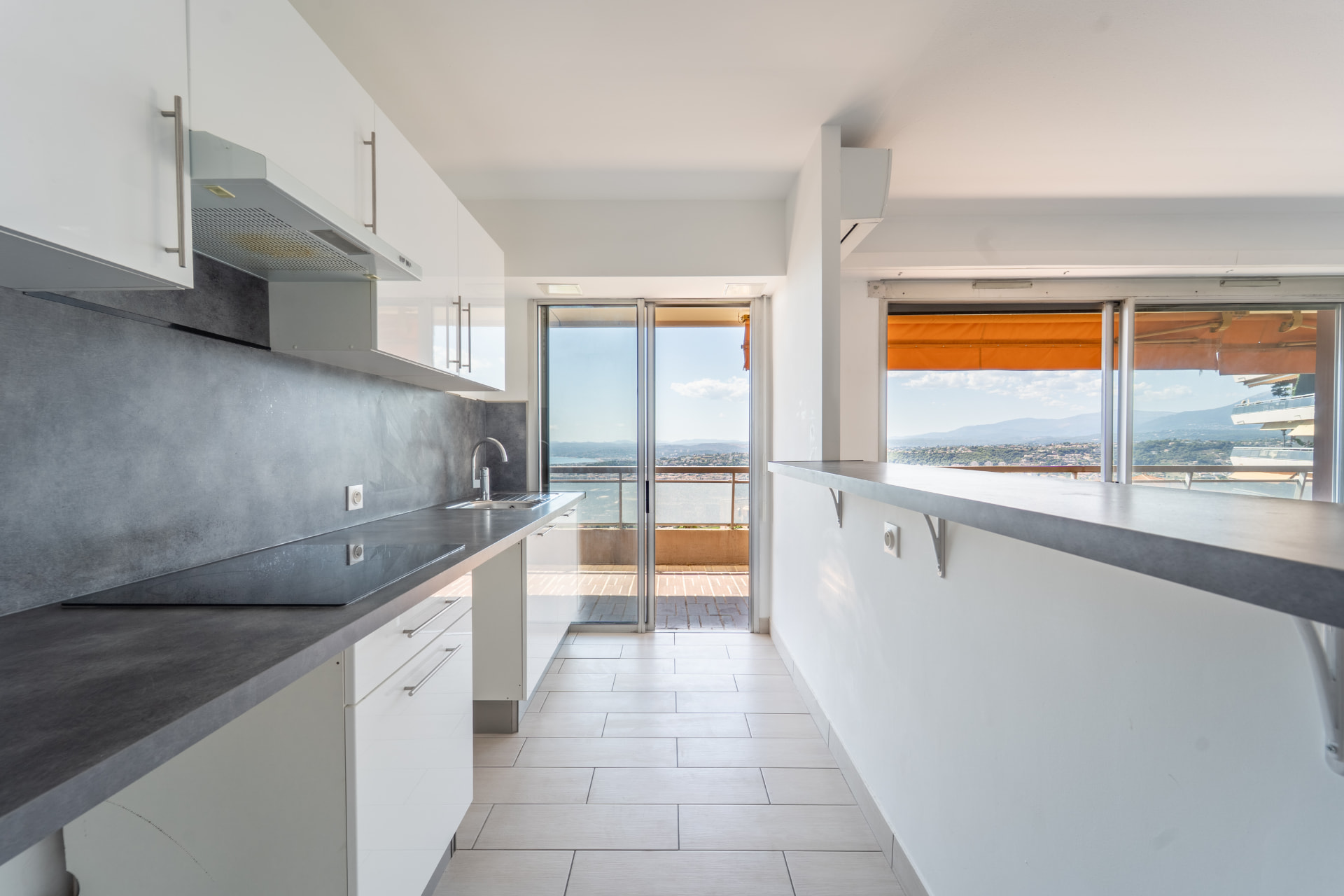 Cuisine moderne lumineuse avec plan de travail anthracite et baies vitrées sur mer
