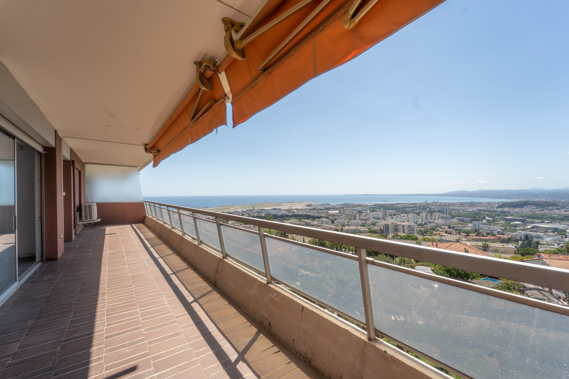 Balcon filant avec store banne et vue panoramique sur la baie et l'aéroport